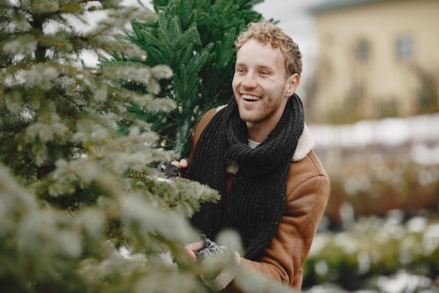 Concepto de invierno. Chico con un abrigo marrón. Vendedor de árbol de Navidad.