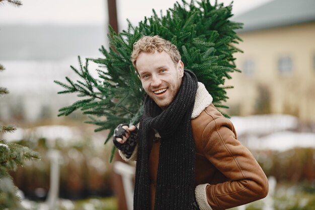 Concepto de invierno. Chico con un abrigo marrón. Vendedor de árbol de Navidad.