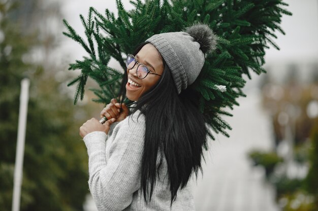 Concepto de invierno. Mujer con un suéter gris. Vendedora de Árbol de Navidad.