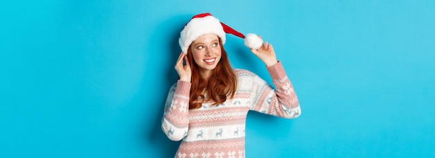 Concepto de invierno y nochebuena linda adolescente con sombrero de santa y suéter celebrando navidad sm