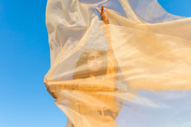 Concepto de libertad con mujer sujetando tela en la naturaleza