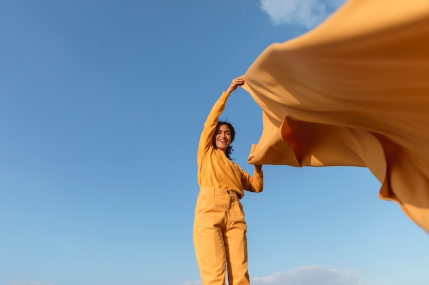 Concepto de libertad con mujer sujetando tela en la naturaleza