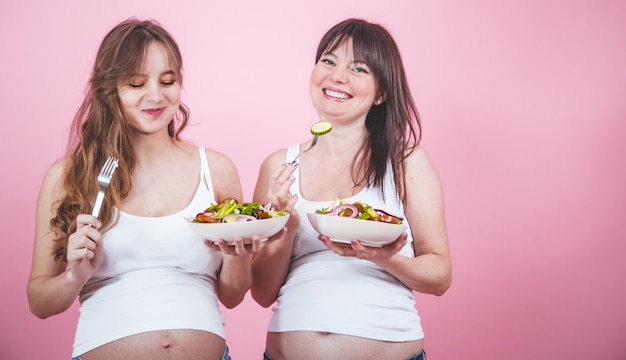 Concepto de maternidad, dos mujeres embarazadas comiendo ensalada fresca