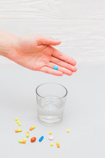 Concepto de medicina con pastillas y mano encima de vaso