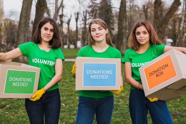 Concepto de medio ambiente y voluntarios con mujeres sujetando cajas para donaciones