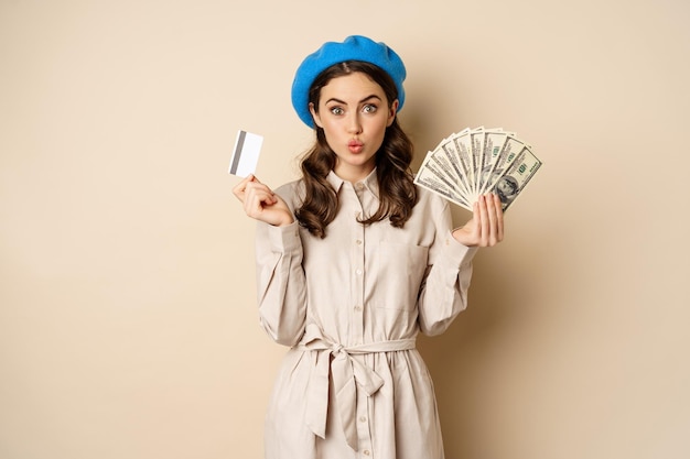 Concepto de microcrédito y dinero mujer elegante joven mostrando tarjeta de crédito y dólares en efectivo sonriendo feliz...