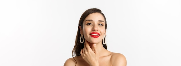 Foto gratuita concepto de moda y belleza primer plano de hermosa mujer morena con labios rojos tocando la cara y sonriendo