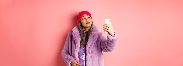 Foto gratuito concepto de moda elegante mujer senior asiática tomando selfie en smartphone posando en piel sintética púrpura co