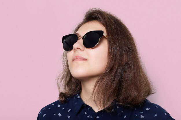 Concepto de moda y estilo. Un elegante elegante joven morena con gafas de sol mirando hacia arriba aislado en blanco. joven modelo con gafas de sol