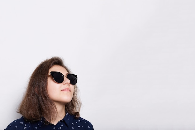 Foto gratuita concepto de moda y estilo. un elegante elegante joven morena con gafas de sol mirando hacia arriba aislado en blanco. joven modelo con gafas de sol