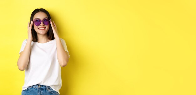 Concepto de moda y estilo de vida elegante mujer asiática probando nuevas gafas de sol en forma de corazón de vacat