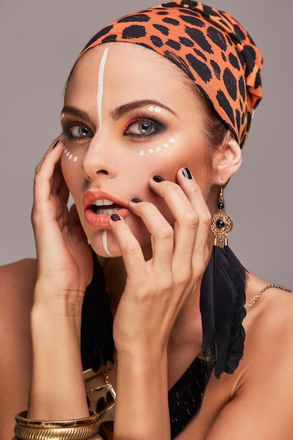 Foto gratuita concepto de moda. hermosa mujer caucásica con maquillaje usando mantón colorido en la cabeza y accesorios. aislado sobre fondo gris.