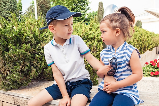 Concepto de moda infantil. chico y chica adolescente sentado en el parque. Ropa colorida para niños, estilo de vida, conceptos de colores de moda.