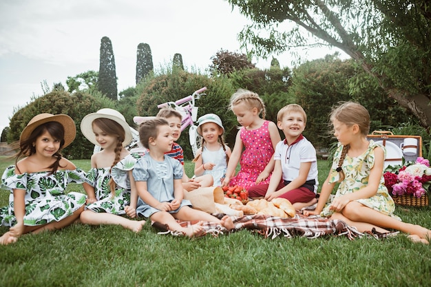 Concepto de moda infantil. El grupo de niños y niñas adolescentes sentados en la hierba verde en el parque. Ropa colorida para niños, estilo de vida, conceptos de colores de moda.