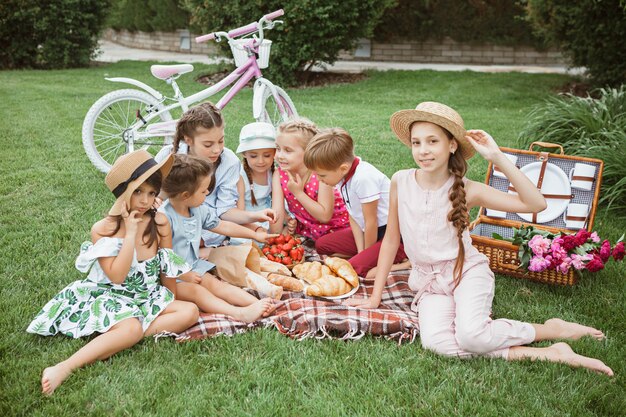 Concepto de moda para niños. El grupo de niños y niñas adolescentes sentados en la hierba verde en el parque.