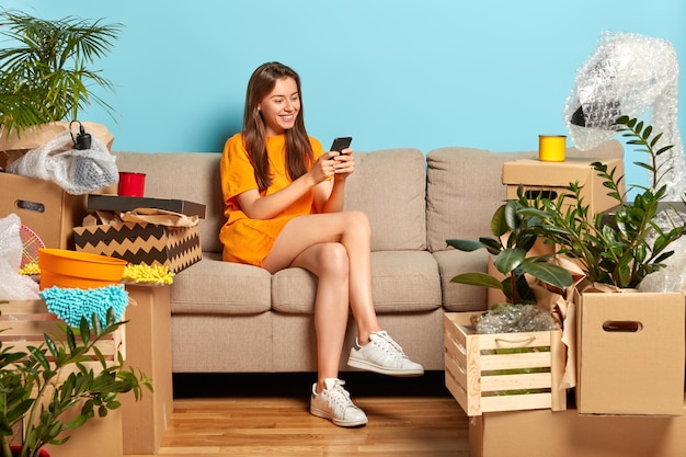 Concepto en movimiento. Modelo de mujer joven alegre rodeado de muchas cajas