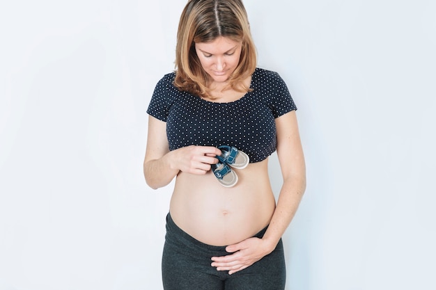 Foto gratuita concepto de mujer embarazada con zapatos de bebé