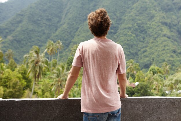 Concepto de naturaleza y libertad. Vista trasera del hombre turista caucásico mirando la selva verde