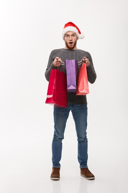Concepto de Navidad atractivo joven caucásico sorprendente regalo impactante en bolsa de compras