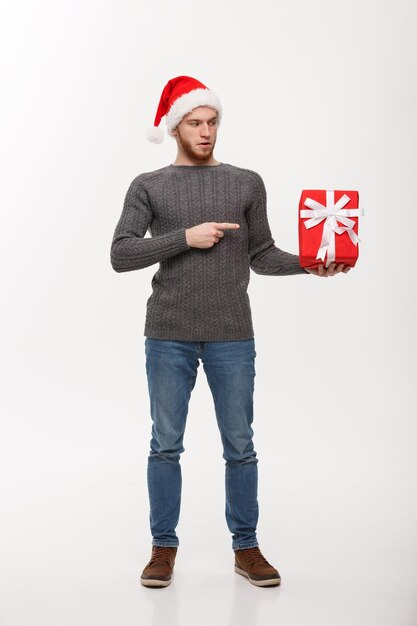 Concepto de Navidad feliz joven con barba dedo acusador presente aislado sobre fondo blanco.