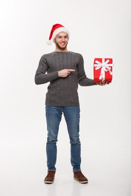 Concepto de Navidad feliz joven con barba dedo acusador presente aislado sobre fondo blanco.