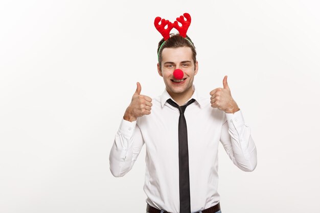 Concepto de Navidad Hombre de negocios guapo con diadema de reno haciendo una expresión facial graciosa