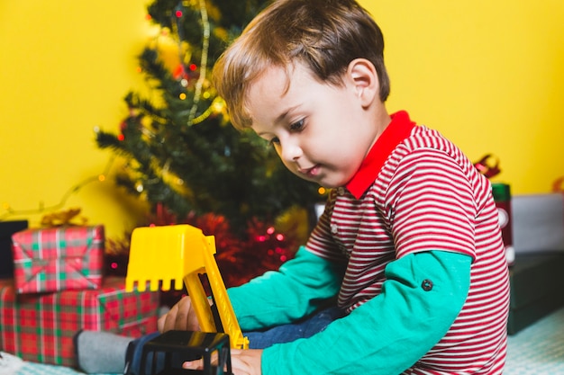 Concepto de navidad con niño jugando enfrente de árbol de navidad