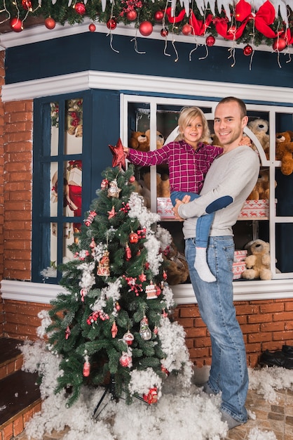 Concepto de navidad con padre e hija enfrente de casa