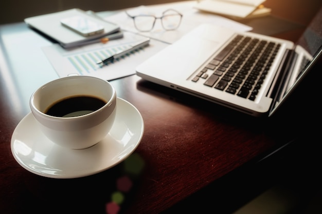 Concepto de negocio con copia espacio. Mesa de escritorio de oficina con enfoque de pluma y análisis de gráfico, computadora, bloc de notas, taza de café en el tablero desk.Vintage Retro filtro, enfoque selectivo.