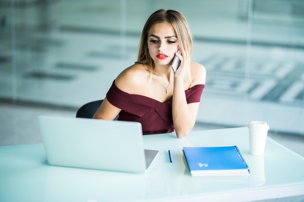 Concepto de negocio - empresaria hablando por teléfono en la oficina