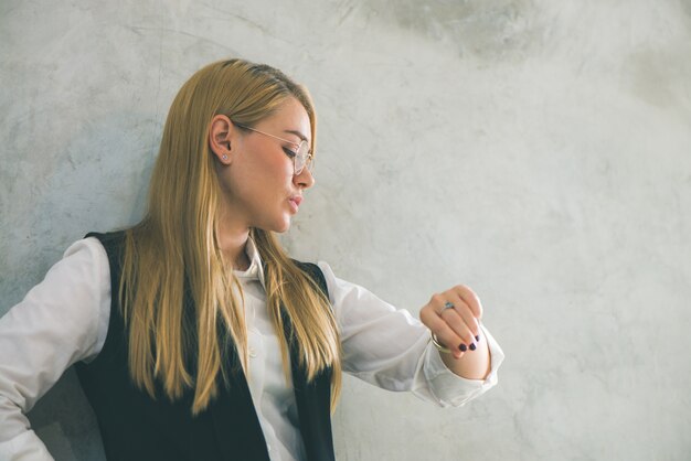 Concepto de negocio y gestión del tiempo. Joven empresaria mirando reloj de pulsera. El tiempo es dinero