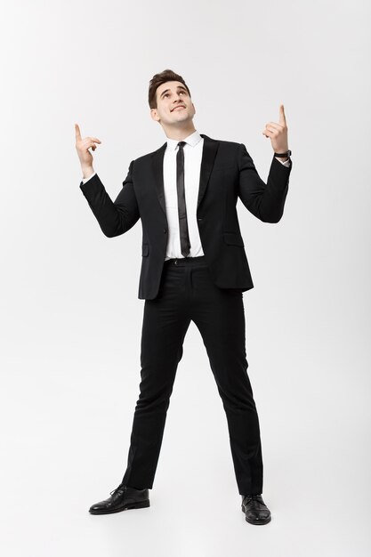 Concepto de negocio: hombre guapo, sonrisa feliz, joven guapo en traje elegante posando dedo acusador sobre fondo gris aislado.