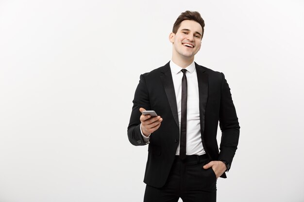 Concepto de negocio: hombre de negocios joven feliz en traje elegante escribiendo sms sobre fondo gris