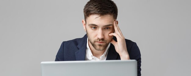 Concepto de negocio retrato apuesto hombre de negocios serio en traje mirando portátil fondo blanco.