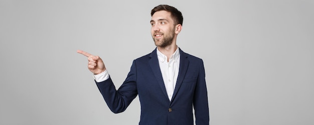 Foto gratuita concepto de negocio retrato guapo hombre de negocios sonrisa confiada apuntando con el dedo fondo blanco.