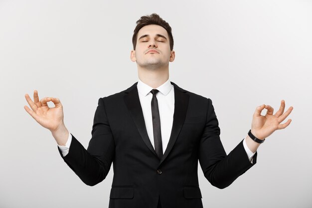 Concepto de negocio - retrato de hombre de negocios caucásico guapo haciendo meditación y yoga antes de trabajar