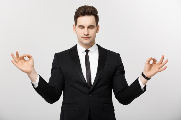 Concepto de negocio - retrato de hombre de negocios caucásico guapo haciendo meditación y yoga antes de trabajar