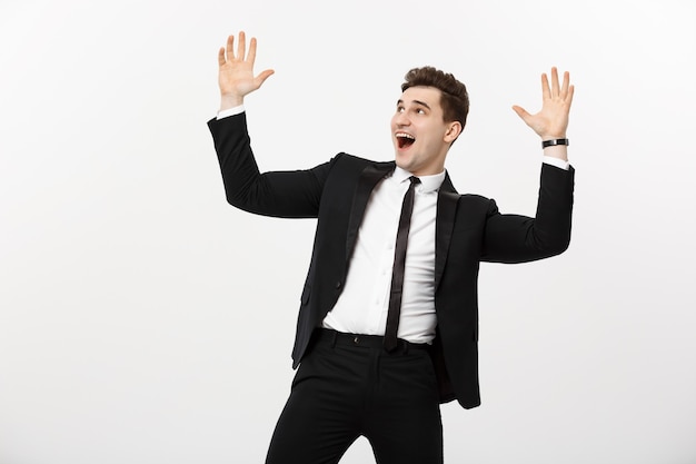 Concepto de negocio: Retrato de hombre de negocios guapo expresando sorpresa y alegría levantando sus manos, aisladas sobre fondo blanco.