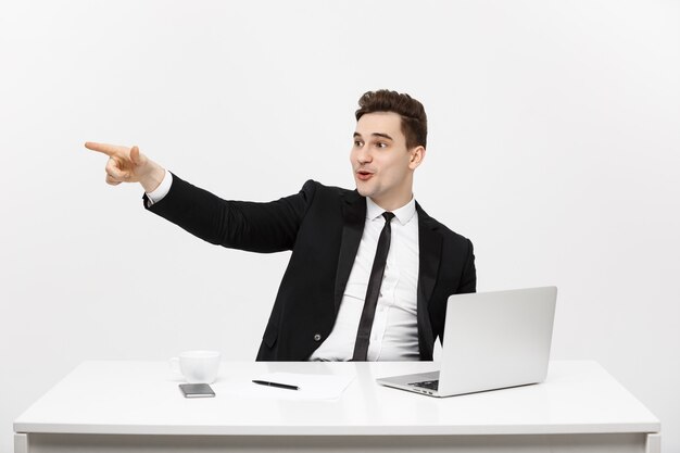 Concepto de negocio retrato de hombre de negocios guapo vestido con traje sentado en la oficina señalando con el dedo ...