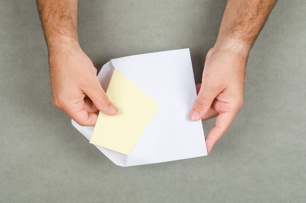 Concepto de negocio en superficie plana gris endecha. Hombre sacando la carta del sobre.