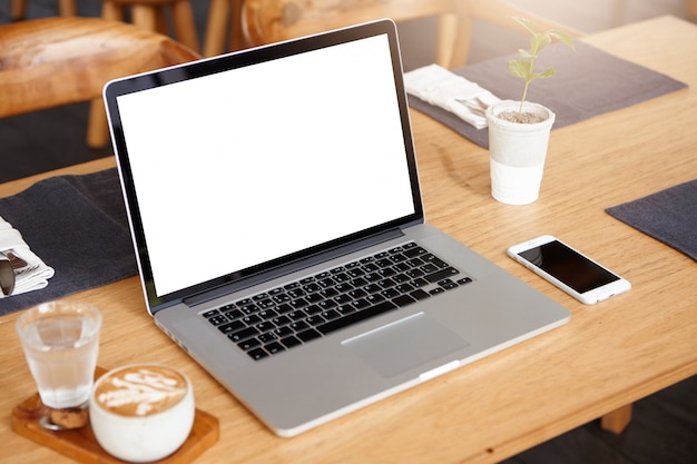 Concepto de negocio, tecnología y comunicación. Espacio de trabajo minimalista con computadora portátil moderna con pantalla blanca en blanco