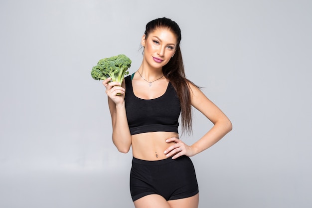 Concepto de nutrición humorística: mujer joven delgada, saludable y en forma con brócoli aislado