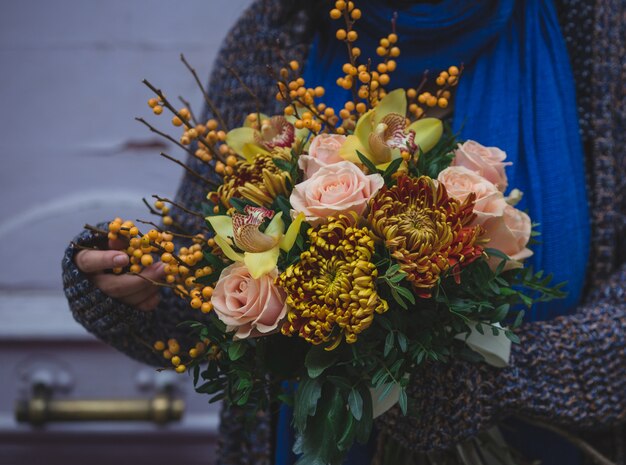 Concepto de otoño ramo de flores y una dama en suéter de lana