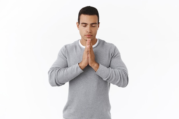 Foto gratuita concepto de paciencia y meditación. calma determinada joven hispana en suéter, rezando a dios