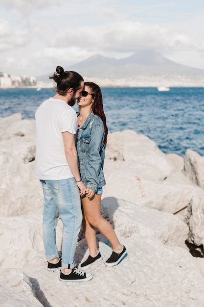 Concepto de pareja y verano en rocas por el mar