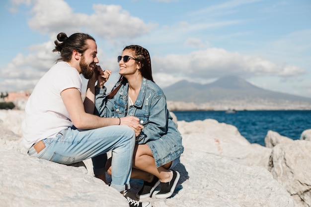 Concepto de pareja y verano en rocas por el mar