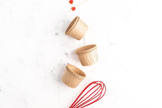 El concepto de pasteles caseros para las vacaciones. Moldes de cupcakes de papel sobre un fondo de piedra blanca. Receta de muffins para San Valentín. Copie el espacio. Vista superior. endecha plana