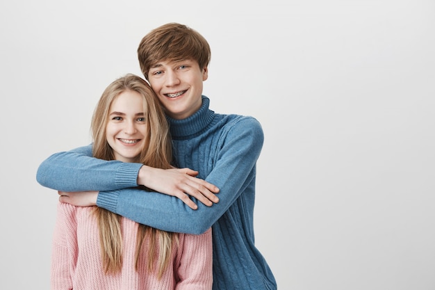 Concepto de personas, amor y relaciones. Dulce foto de la feliz pareja sonriente vestida casualmente abrazos