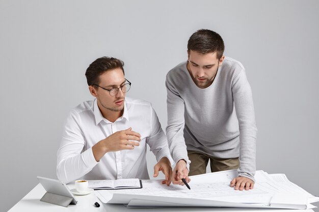 Foto gratuita concepto de personas, cooperación y trabajo en equipo. hombres profesionales talentosos trabajan en dibujos,