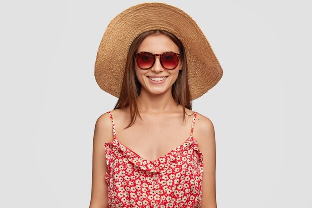 Concepto de personas y descanso. Preciosa turista satisfecha en tonos de moda, vestido y sombrero de verano. Turista tiene vacaciones